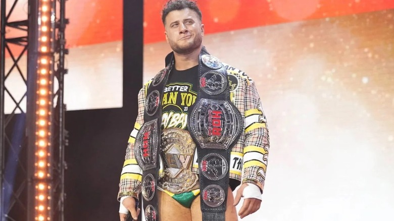 The former AEW World and ROH World Tag Team Champion, MJF, expresses a cheeky grin while carrying both titles