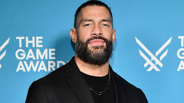 Roman Reigns wearing a black shirt and jacket