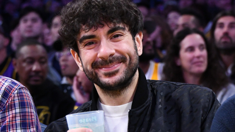 AEW CEO Tony Khan smiles as he holds a cup.