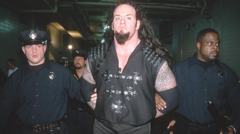 The Undertaker being escourted away by police after a storyline during the 