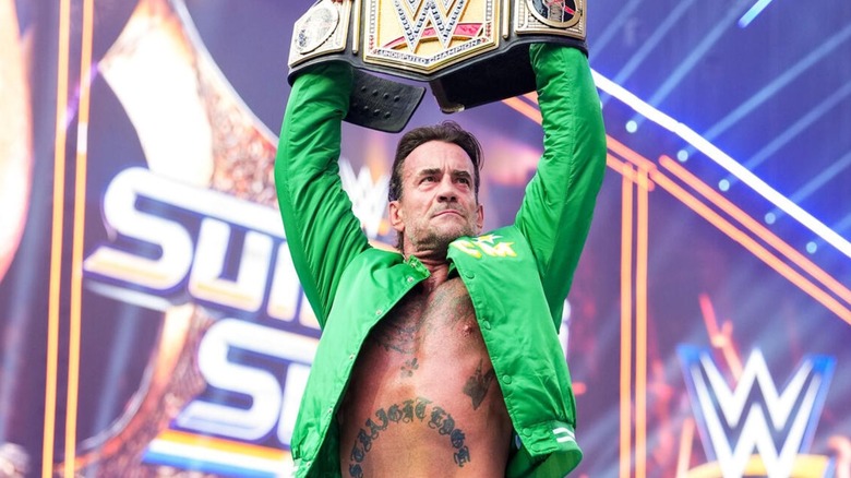 Undisputed WWE Champion CM Punk hoists the title belt high above his head before defending the gold against Cody Rhodes at WWE SummerSlam 2026.