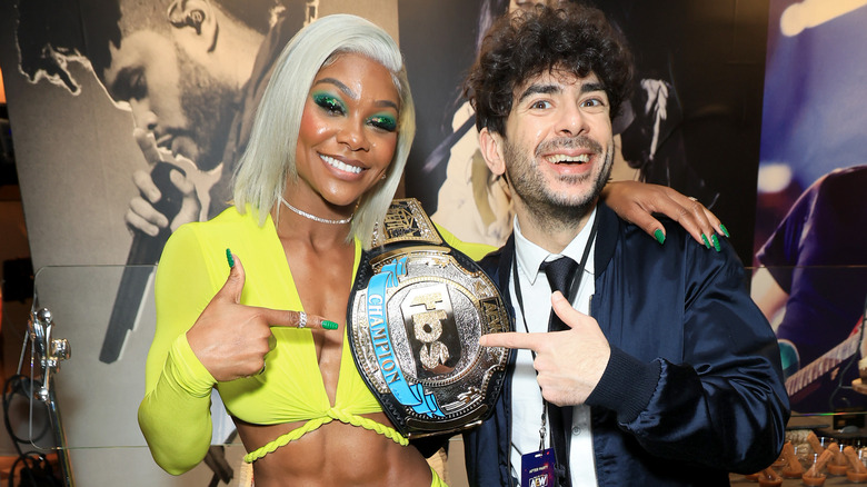 Tony Khan and Jade Cargill smiling and pointing at the TBS logo