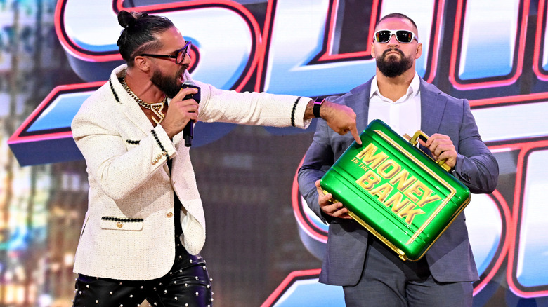 Seth Rollins pointing to the Money in the Bank briefcase, held by Bron Breakker