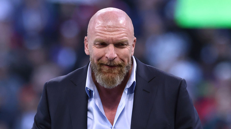Triple H grinning while looking at the ground