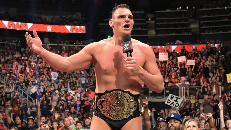 Intercontinental Champion Gunther stands above a crowd at WWE Raw with a microphone in his hand.