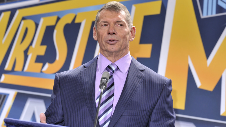 WWE's Vince McMahon standing in front of a WrestleMania banner