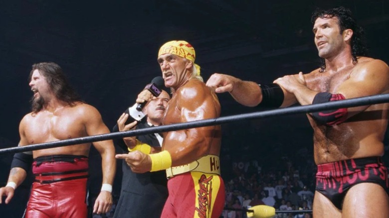 Hulk Hogan on the mic, standing between Kevin Nash and Scott Hall at Bash at the Beach 1996