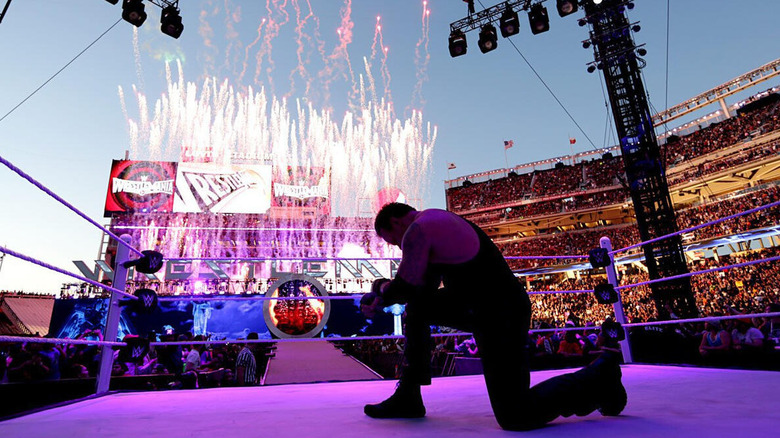 The Undertaker poses in the ring, with fireworks going off around the tron, following his victory over Bray Wyatt at WrestleMania 31.