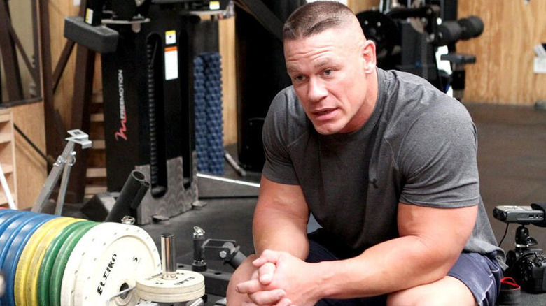 John Cena sitting on a weight bench in a fitness gym