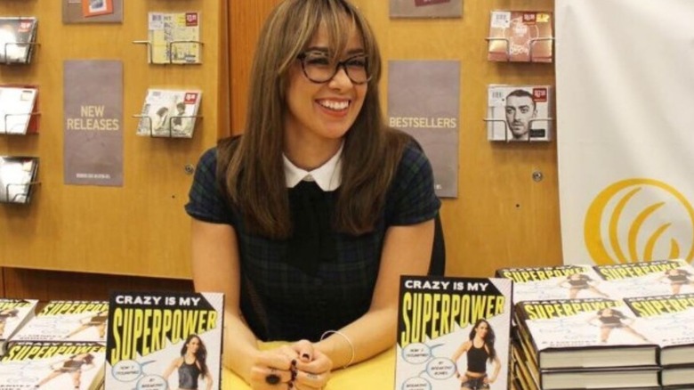 AJ Lee poses behind a table at a book signing for her memoir "Crazy is my Superpower."