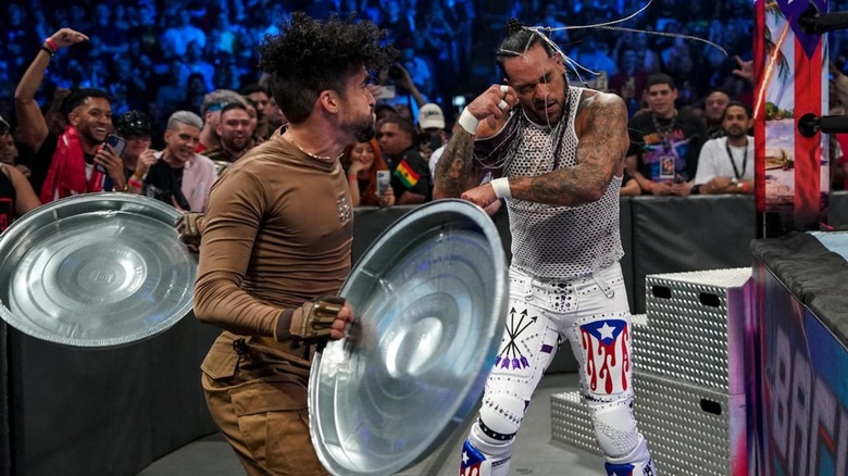 Bad Bunny prepares to hit Damian Priest with a trash can lid during their street fight at WWE Backlash.