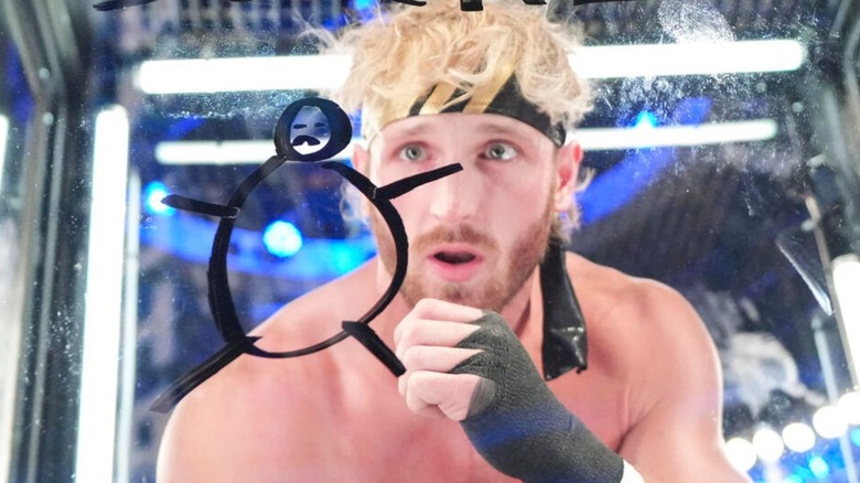 Logan Paul draws on the glass of the Elimination Chamber pod to intimidate Kevin Owens during the match.