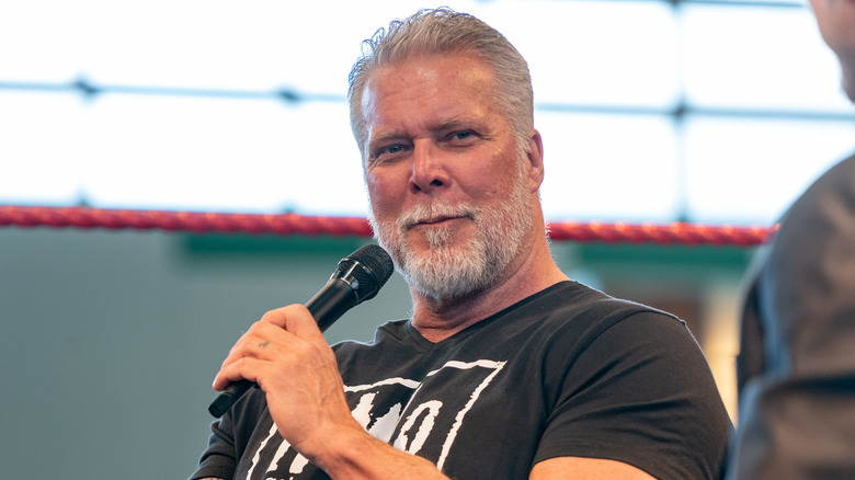 Kevin Nash holding a mic and looking amused