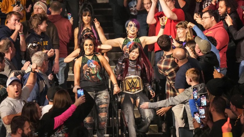 Bayley, IYO SKY, Asuka, and Dakota Kai head to the ring through the crowd on an episode of "WWE Raw."