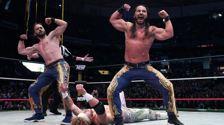 Matthew and Nicholas Jackson flex their arms over a grounded Will Ospreay.