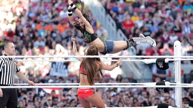 AJ Lee hits a flying cross body to Nikki Bella in the ring during their tag team match at WrestleMania 31.
