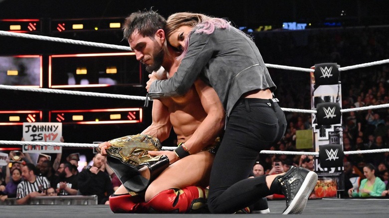 Candice LeRae hugs husband Johnny Gargano in the ring, as he clutches the NXT Championship, after his victory over Adam Cole at NXT TakeOver New York.