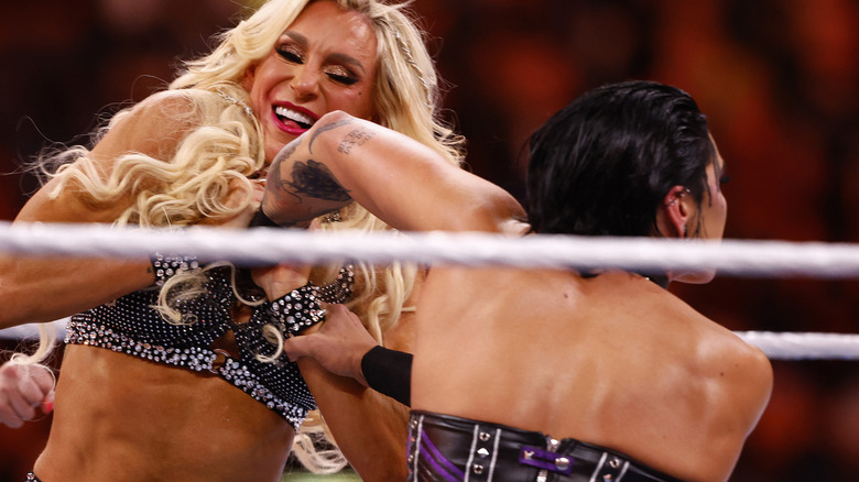 Rhea Ripley and Charlotte Flair locking up in the ring.