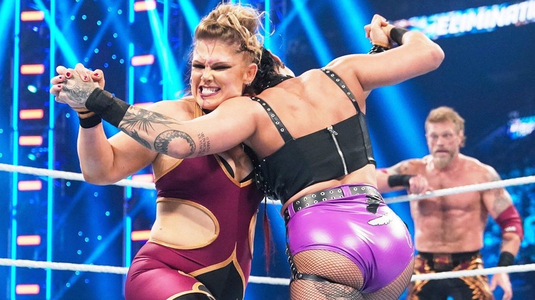 Beth Phoenix grapples with Rhea Ripley while Edge looks on at WWE Elimination Chamber 2023