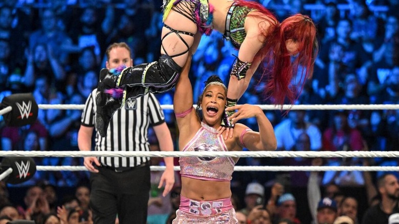 Bianca Belair presses IYO SKY over her head in the middle of the ring during their match at Backlash in 2023.