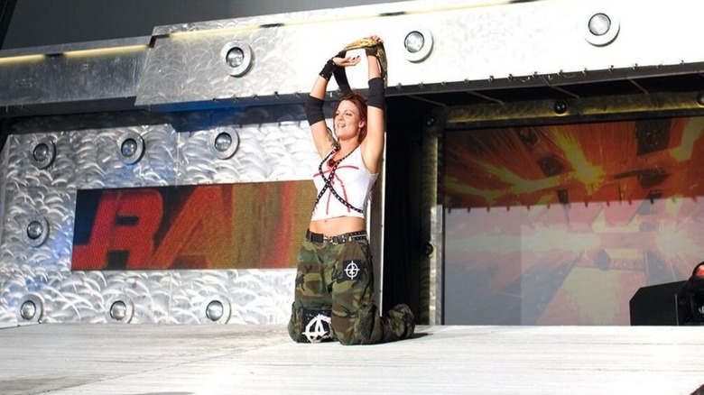 Lita holds up the WWE Women's Championship over her head after a victory over Trish Stratus in the main event of 