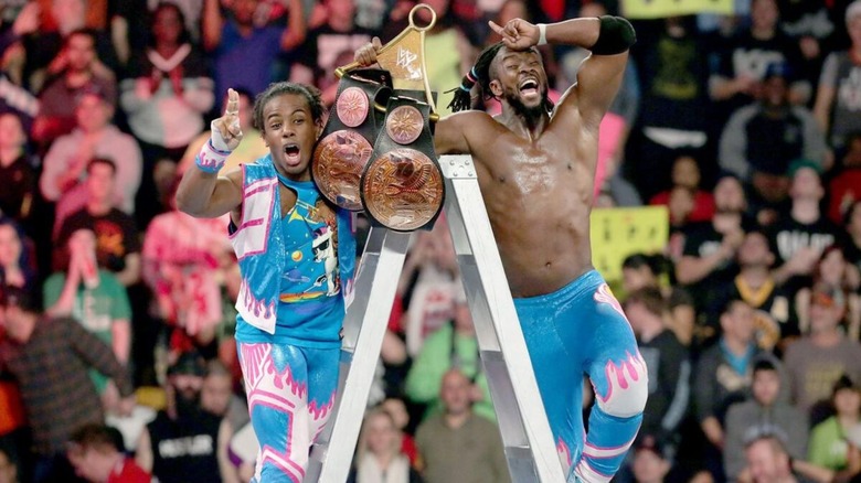 Kofi Kingston and Xavier Woods stand atop the ladder with the WWE Tag Team Championships in hand after winning the ladder match at TLC.