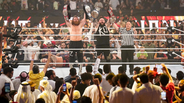 Sami Zayn and Kevin Owens hold up the WWE Undisputed Tag Team Championship titles at Night of Champions 2023.