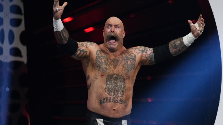 The Butcher stops on the stage to raise his arms and pose for fans before heading down to the ring for a match on a February 2025 edition of "AEW Collision."