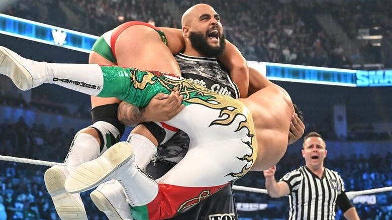 Top Dolla hoists two competitors in the ring during a match on "WWE SmackDown."