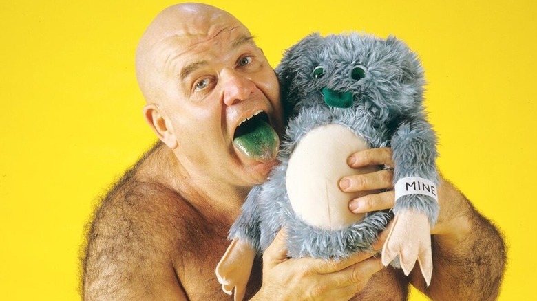 George "The Animal" Steele holds on to a stuffed animal in a photo where he poses with his tongue, stained green, sticking out.