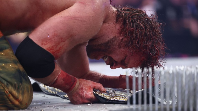 "Hangman" Adam Page kneels down towards the AEW World Championship after a bloody Texas Death Match.