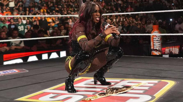 Naomi holding a microphone, while squatting