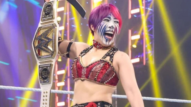 Former women's champion Asuka holds up the title in the ring on "WWE SmackDown."