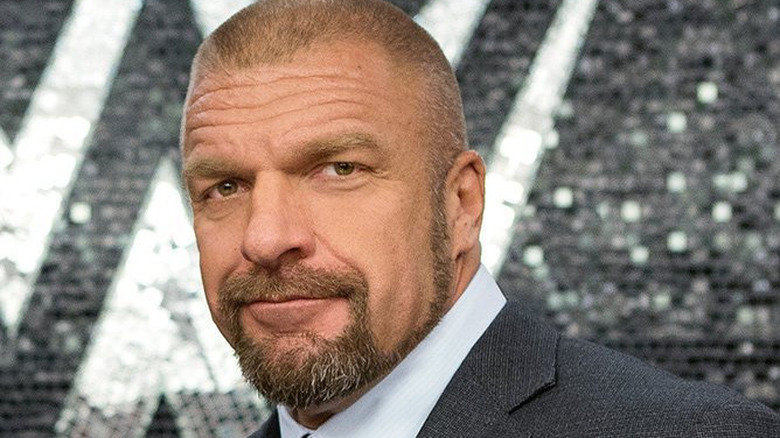 WWE CCO Triple H in a suit, smiling