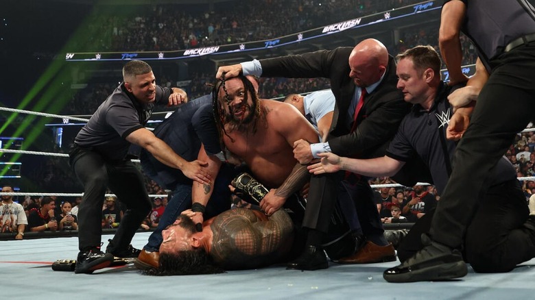 Officials try to drag Jacob Fatu off a prone Roman Reigns at WWE Backlash