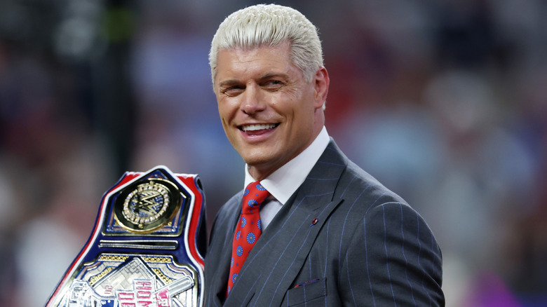 Cody Rhodes smiling and holding a championship belt