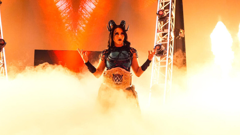 Stephanie Vaquer poses among smoke, with the WWE Women's World Championship around her waist.