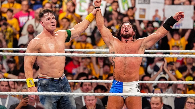 John Cena holds up the arm of AJ Styles in the ring after defeating him at Crown Jewel.