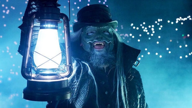 Uncle Howdy holds up the lantern during his entrance, fireflies behind him, on an episode of 