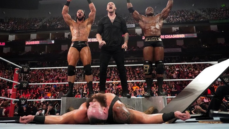 Baron Corbin, Drew McIntyre, and Bobby Lashley stand over Braun Strowman at WWE Elimination Chamber 2019