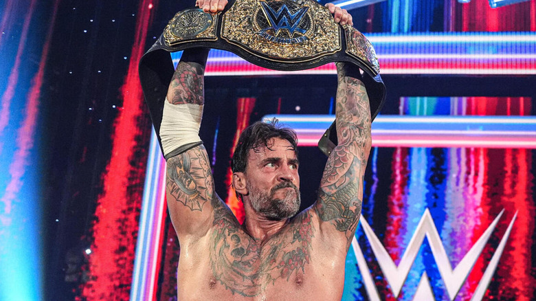 CM Punk hoists up the WWE World Heavyweight Championship