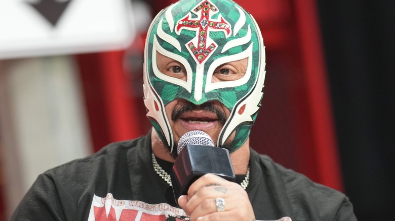 Rey Mysterio is holding a microphone