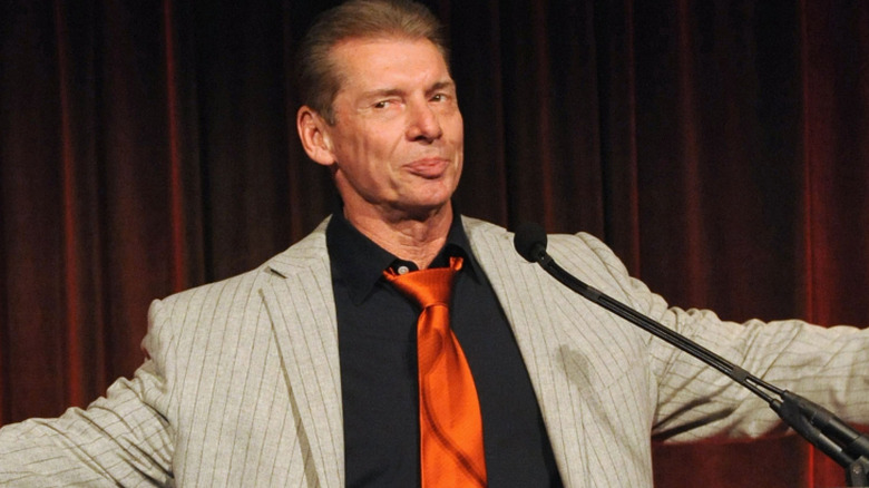 Vince McMahon stands at a speech-giving podium.