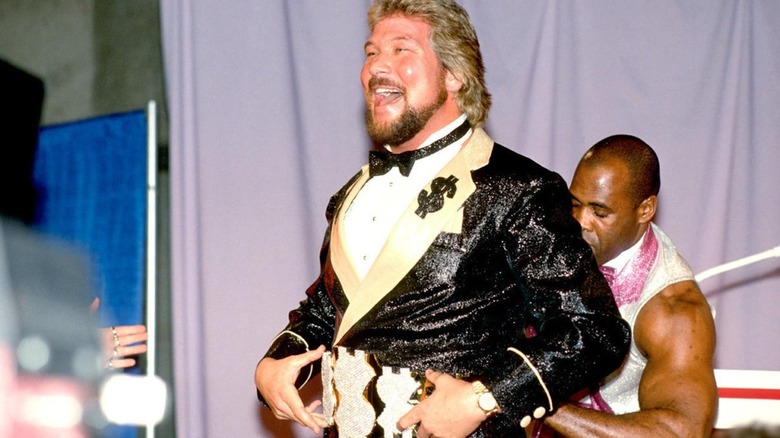 Ted DiBiase laughs as Virgil straps his belt