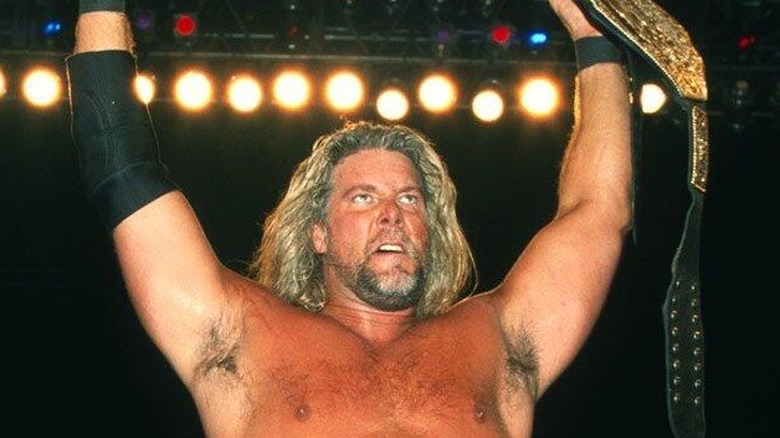 Kevin Nash proudly holds up the WCW World Heavyweight Championship after winning it.