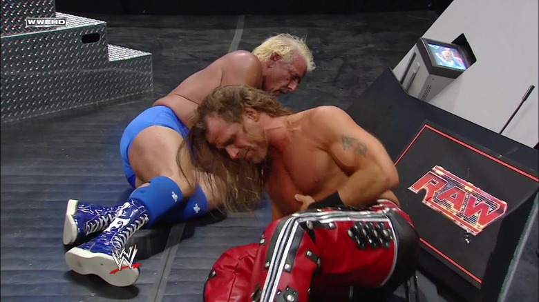 Ric Flair and Shawn Michaels reeling after HBK hit a Diving Moonsault spot onto the outside table.