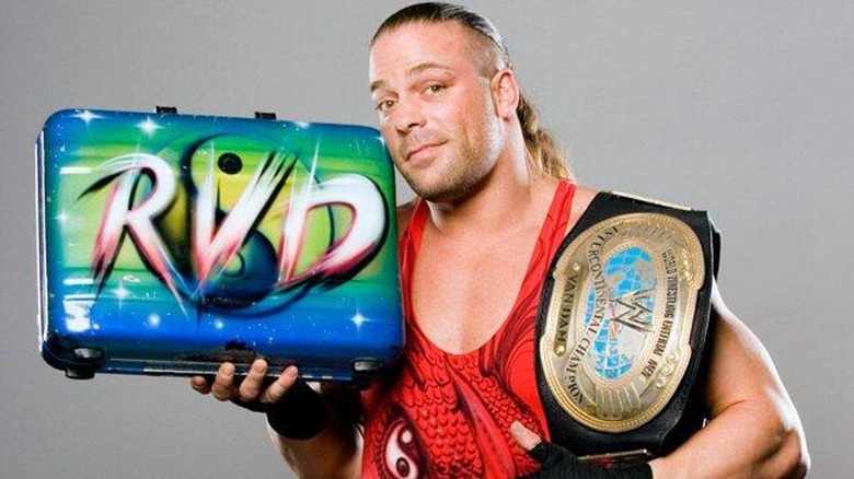 Rob Van Dam posing with his custom Money in the Bank Briefcase and the WWE Intercontinental Championship for a promotional photoshoot.