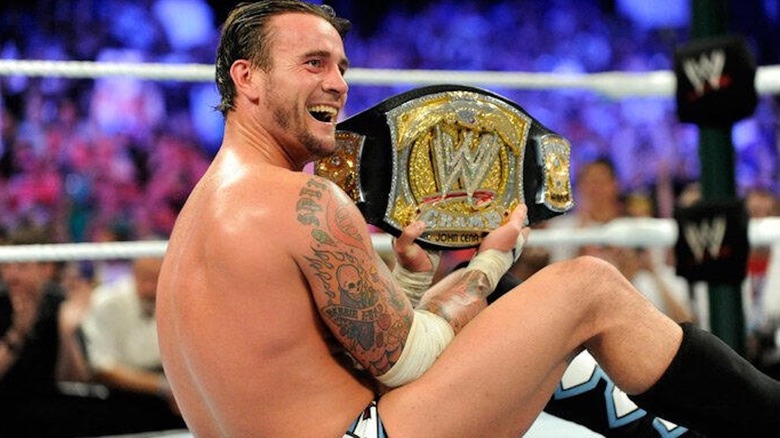 CM Punk grins while holding the WWE Championship at WWE Money in the Bank 2011
