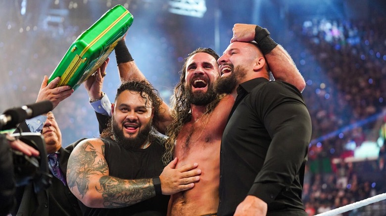 Seth Rollins celebrates his second Money in the Bank ladder match win with Bron Breakker and Bronson Reed while holding the briefcase aloft at WWE MITB 2025