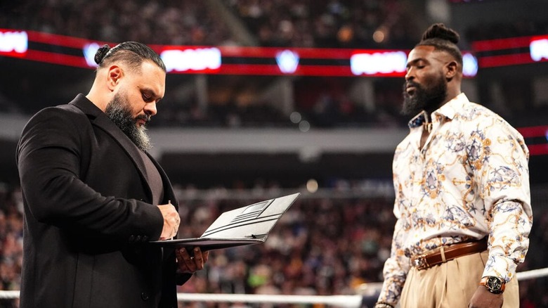 Oba Femi looks on as Bronson Reed signs the contract for their WWE Money in the Bank 2026 match in the ring during an episode of "WWE Raw."